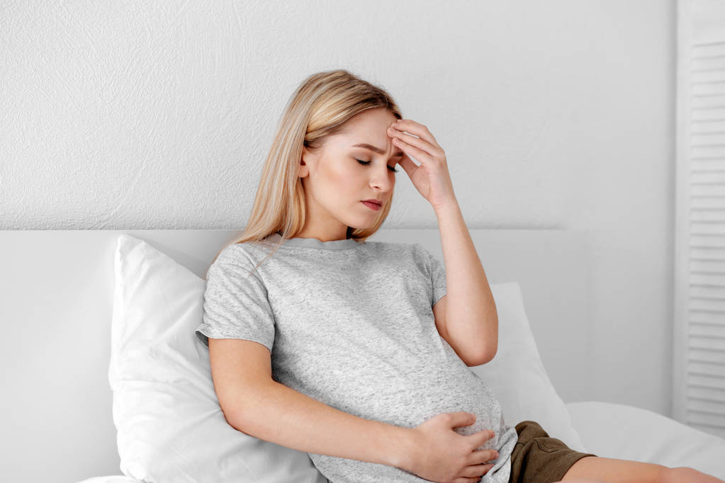 Jeune femme enceinte souffrant de maux de tête à la maison - Photo, image