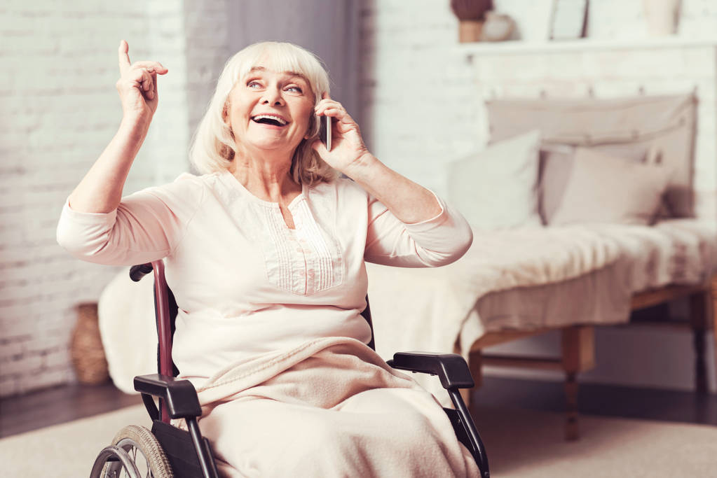 Радостная старуха-инвалид разговаривает по телефону дома
 - Фото, изображение