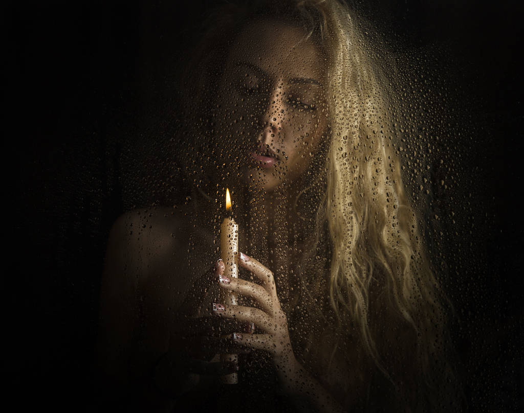 curly nude blonde woman with candle on dark background - Photo, Image