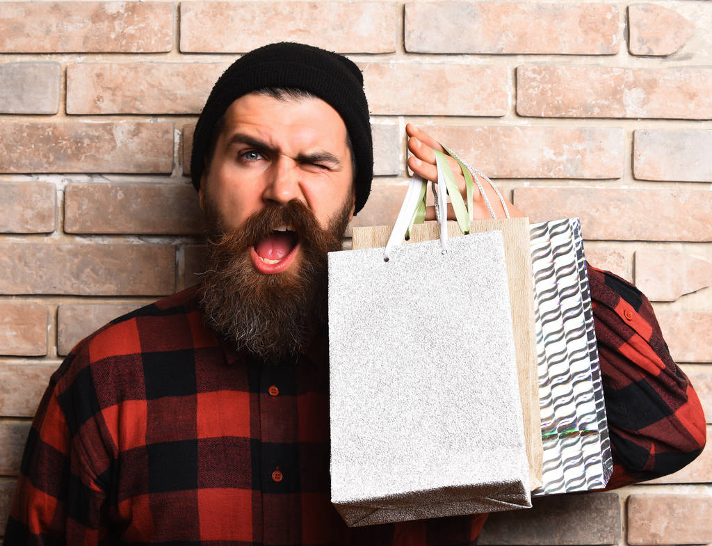 Γενειοφόρος βάρβαρος καυκάσιος χίπστερ με μουστάκι που κρατάει πακέτα αγορών - Φωτογραφία, εικόνα