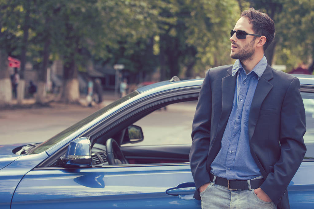 Успешный красивый мужчина, стоящий у своей новой машины, наслаждаясь летним днем
  - Фото, изображение