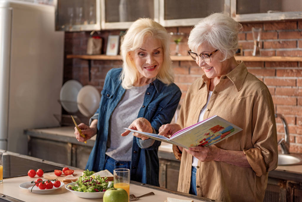 Iloiset vanhat naiset lukemassa keittiössä
 - Valokuva, kuva