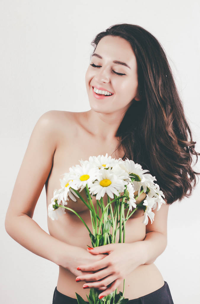 tierna linda hermosa chica joven de verano con el cuerpo en topless piel perfecta. sostiene manzanillas flores. fondo blanco
 - Foto, imagen