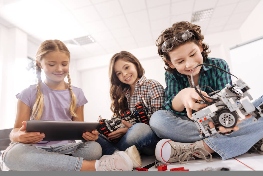 Crianças em idade escolar usando dispositivos no estúdio ciência a sorrir - Foto, Imagem