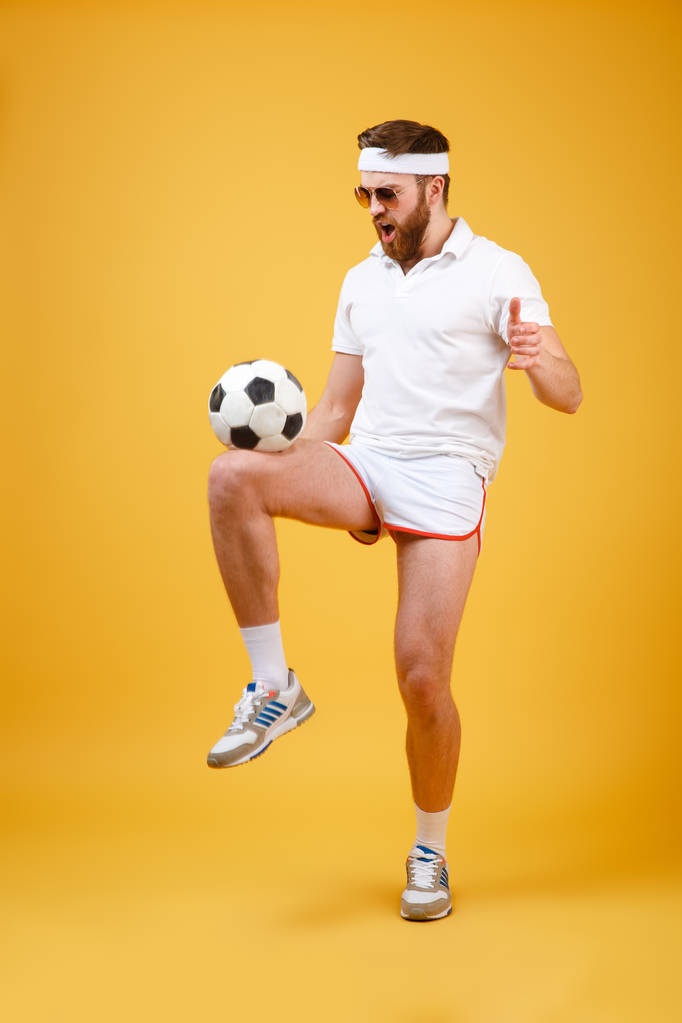 Guapo joven deportista emocional hacer ejercicios de fútbol con pelota
 - Foto, Imagen