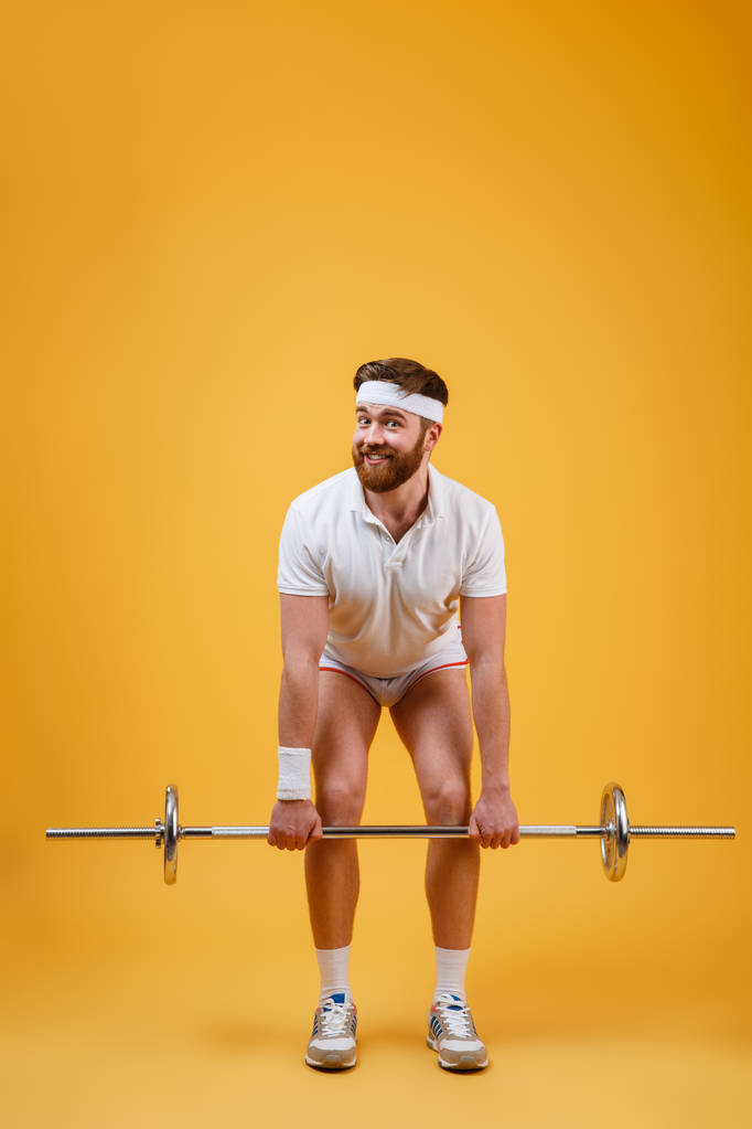 Полная длина спортивного человека, делающего упражнения на корточках с штангой
 - Фото, изображение