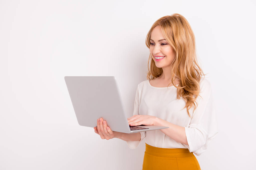 Jeune femme blonde souriante tenant un ordinateur portable et tapant dessus
 - Photo, image
