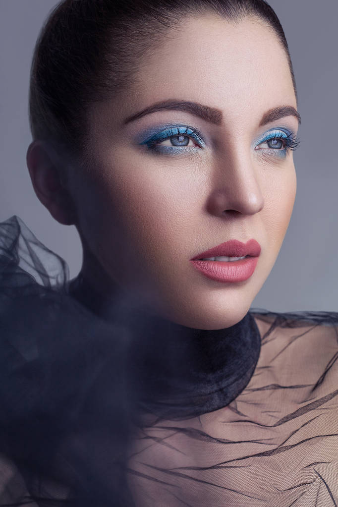 Retrato de modelo de moda bonita morena com véu preto e maquiagem azul em prateado chão de padaria preto
.  - Foto, Imagem