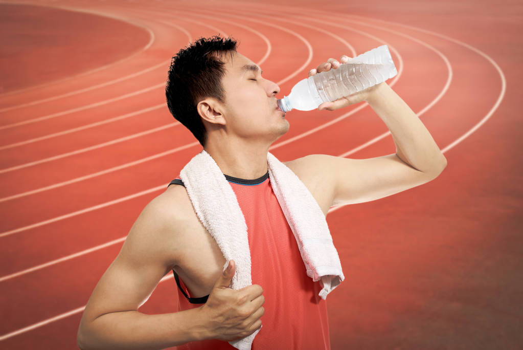 janoinen nuori aasialainen komea urheilija juomaveden jälkeen pitkällä aikavälillä
 - Valokuva, kuva
