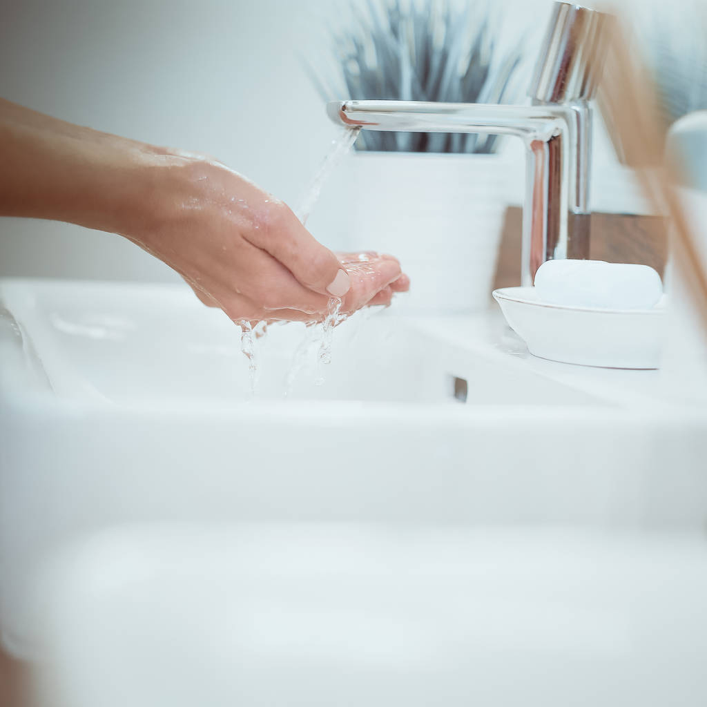 Mujer joven lavándose la cara con agua limpia en el baño - Foto, imagen