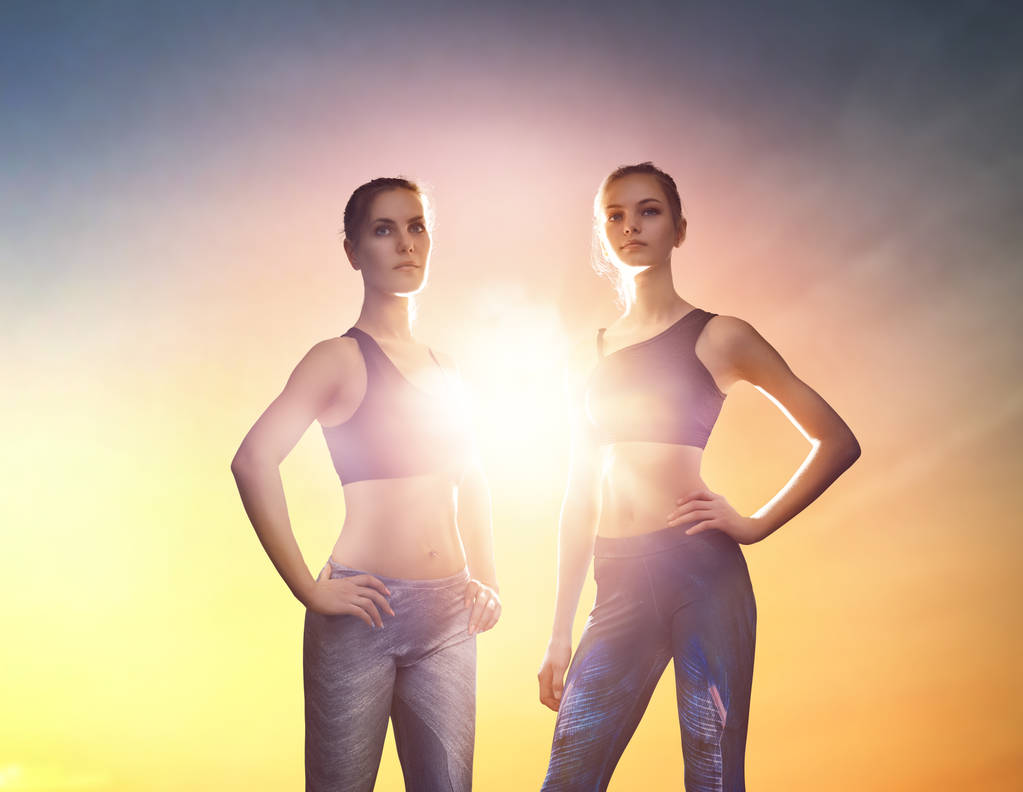 zwei Sportmädchen im Hintergrund des Sonnenuntergangs. - Foto, Bild