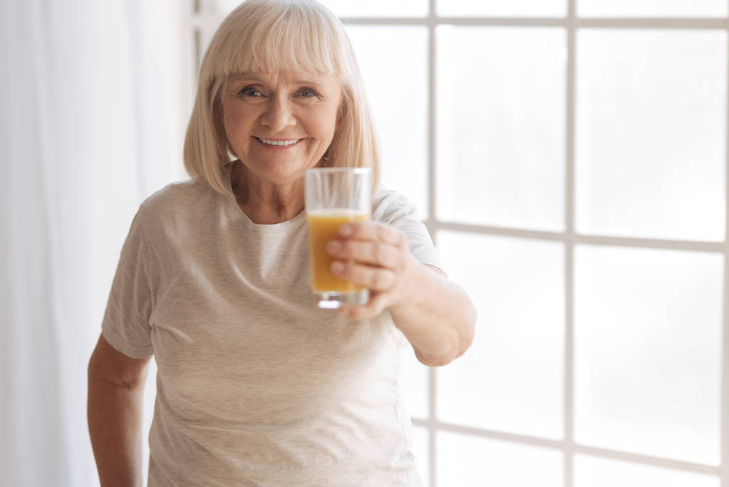 Feliz anciana que le ofrece un vaso de jugo
 - Foto, imagen