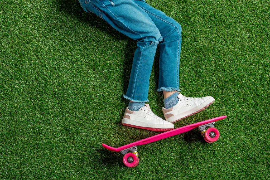 Girl with skateboard lying on grass  - Photo, Image