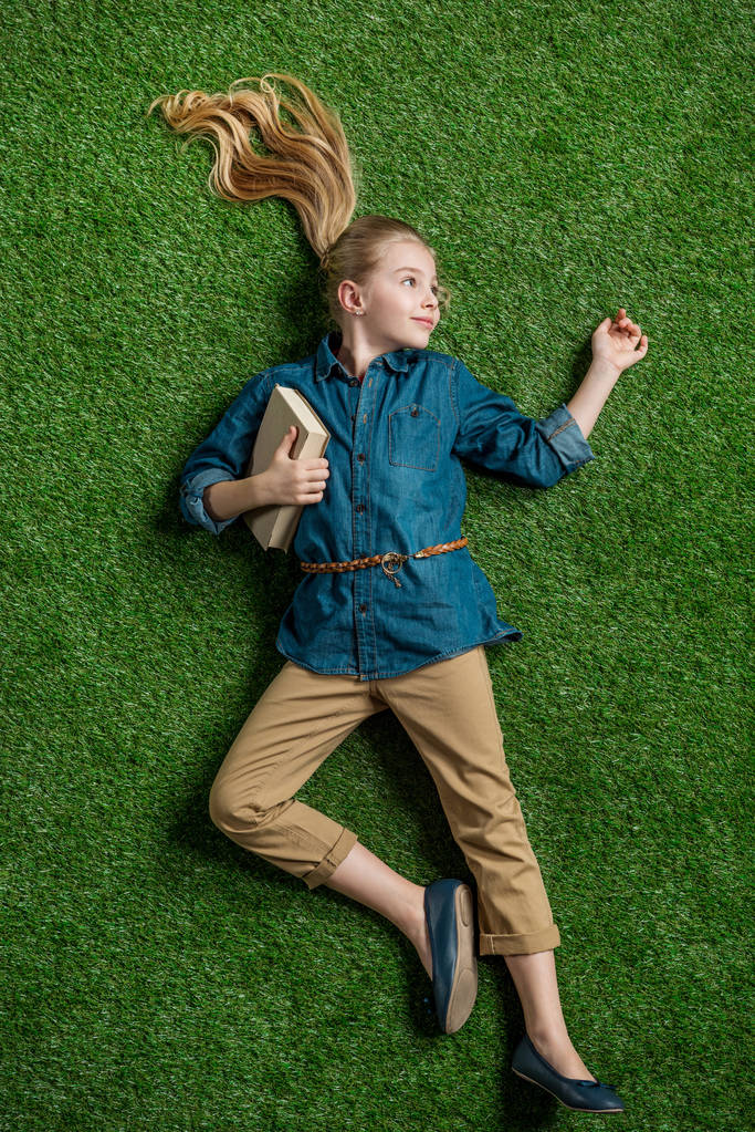 Chica con libro acostado en la hierba
  - Foto, Imagen