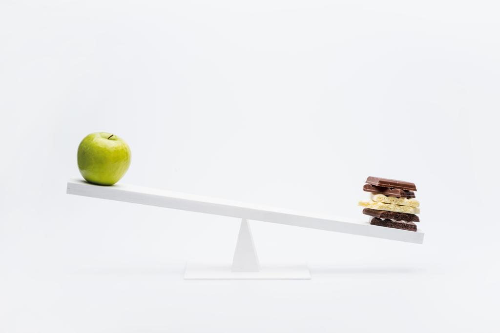 Apple and chocolate on seesaw  - Photo, Image