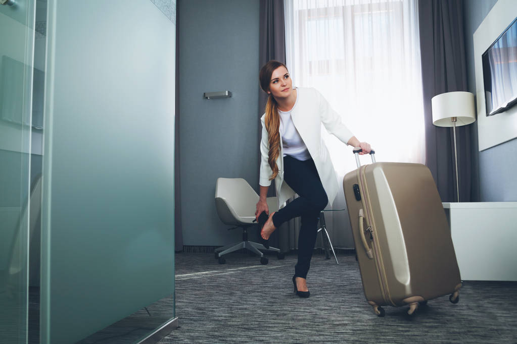 Mujer tirando de la maleta en la habitación de hotel moderna
 - Foto, Imagen