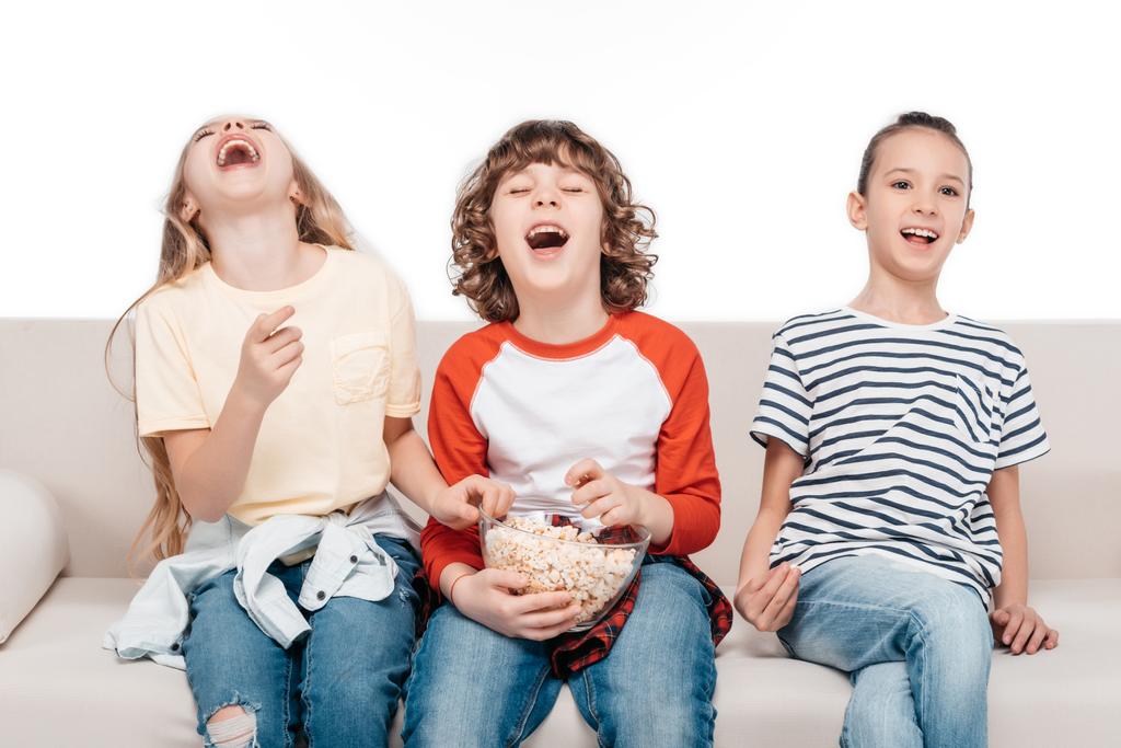 Lindos niños en el sofá con palomitas de maíz
 - Foto, Imagen