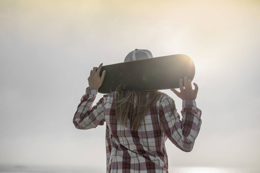 mladá žena držící skateboard - Fotografie, Obrázek