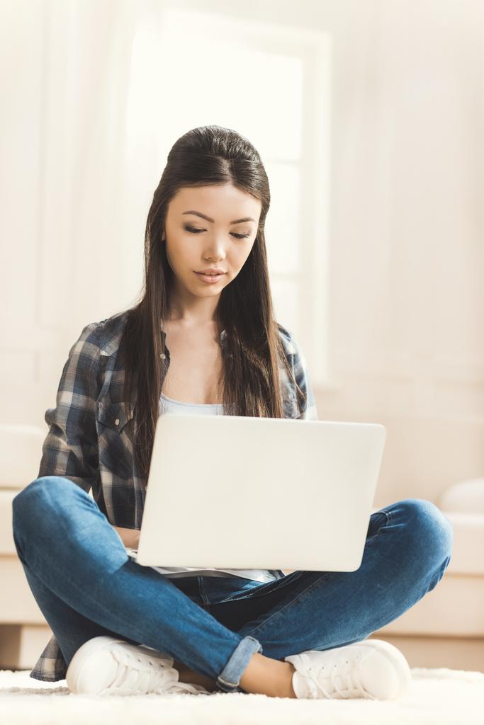 femme assise sur le sol et travaillant sur ordinateur portable
 - Photo, image