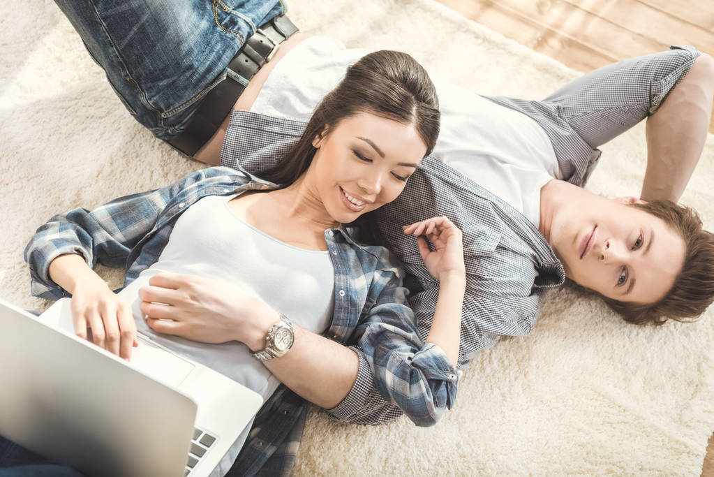woman lying on boyfriend and using laptop - Photo, Image