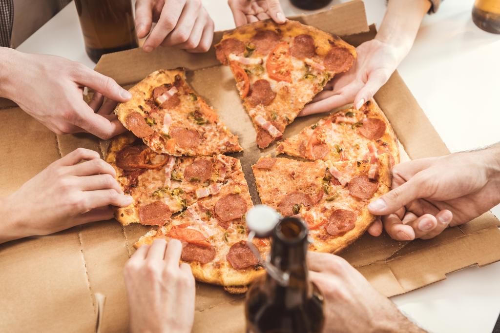 manos humanas sosteniendo rebanadas de pizza
 - Foto, Imagen