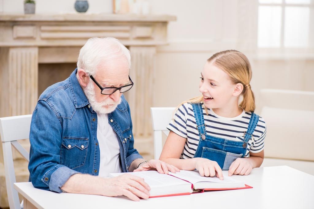 Abuelo con libro de lectura de chica
 - Foto, Imagen