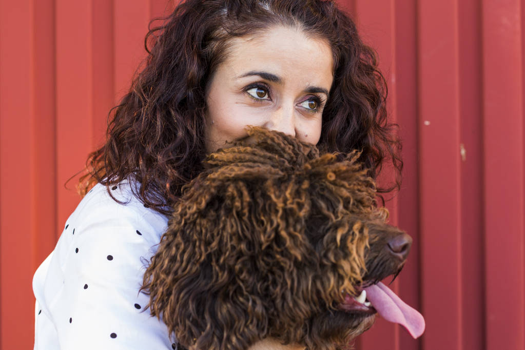 Bella giovane donna che abbraccia il suo cane, un cane d'acqua marrone spagnolo
 - Foto, immagini