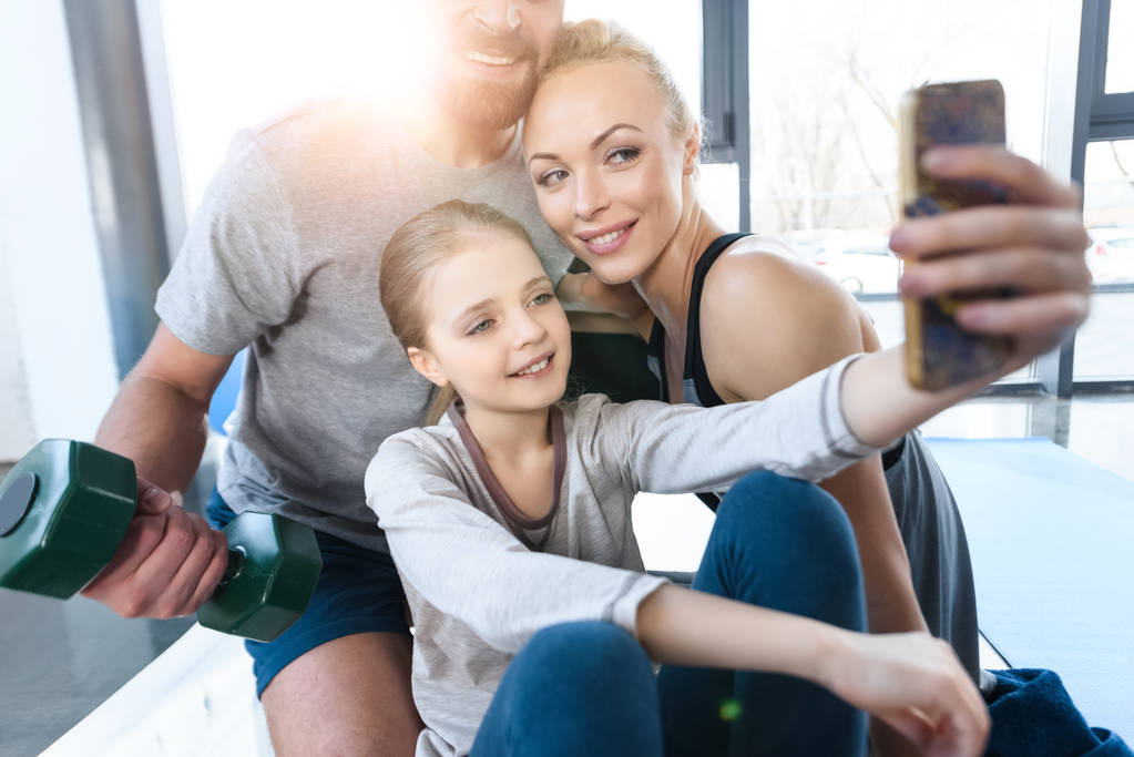 Girl taking self portrait with parents at fitness center - Photo, Image