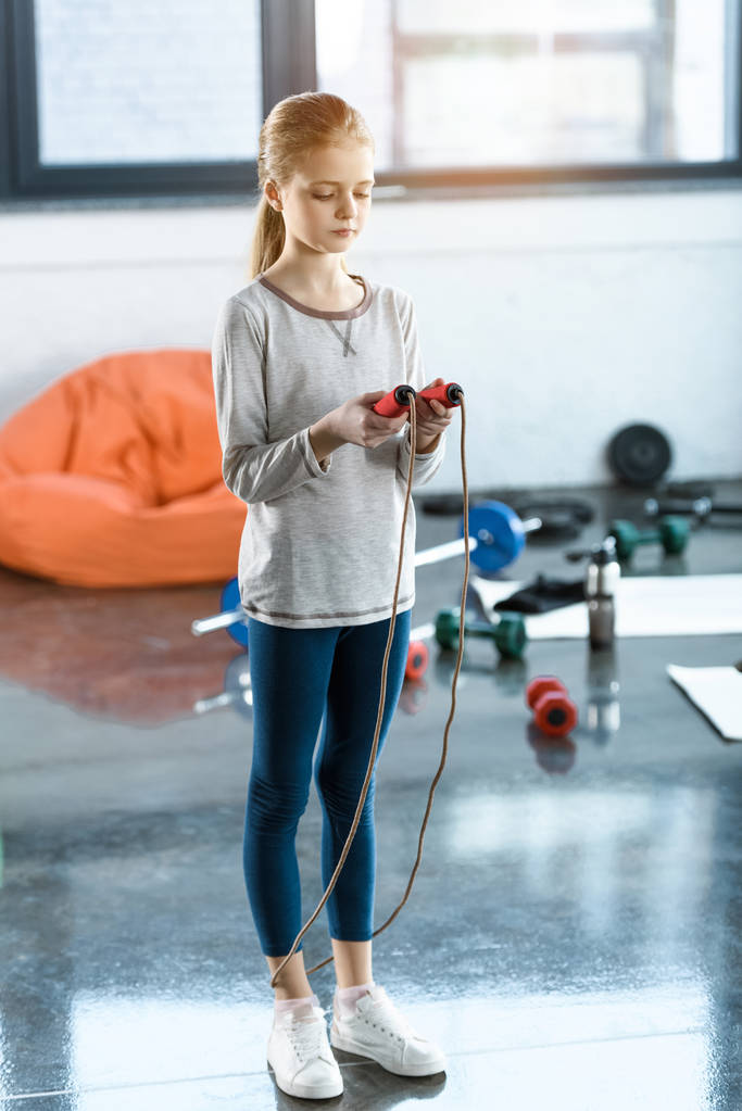 Jong meisje met springtouw op fitness-studio - Foto, afbeelding