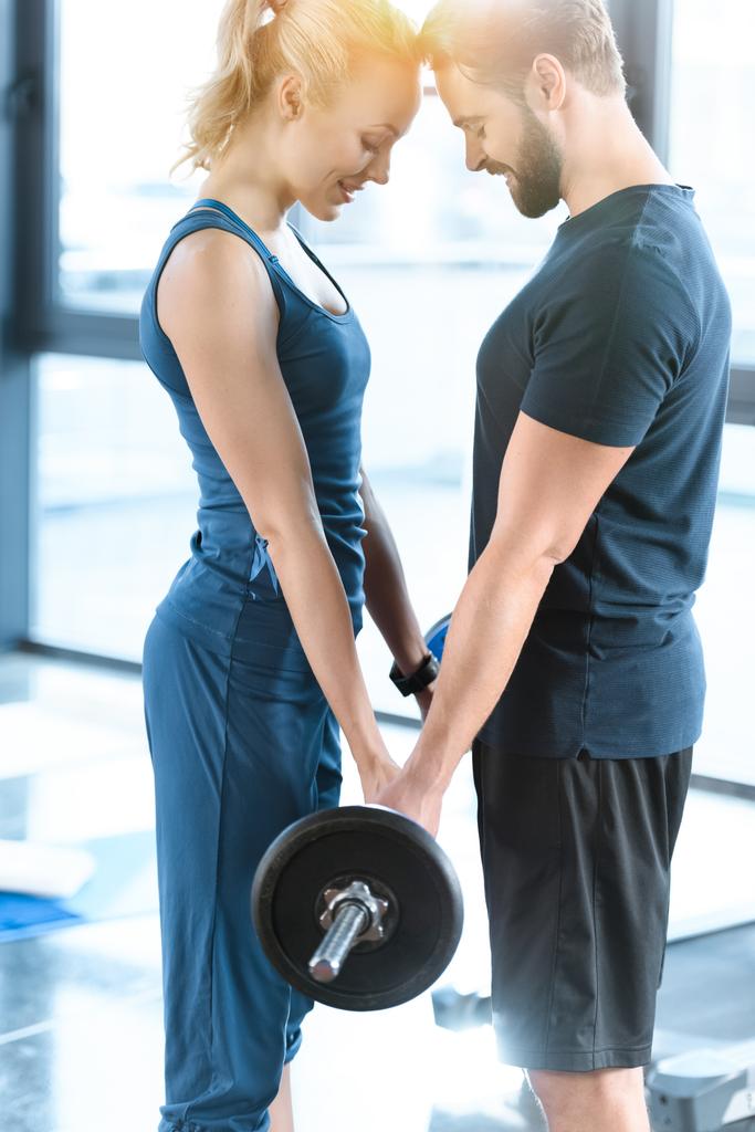 Loving couple exercising together with barbell at gym - Photo, Image