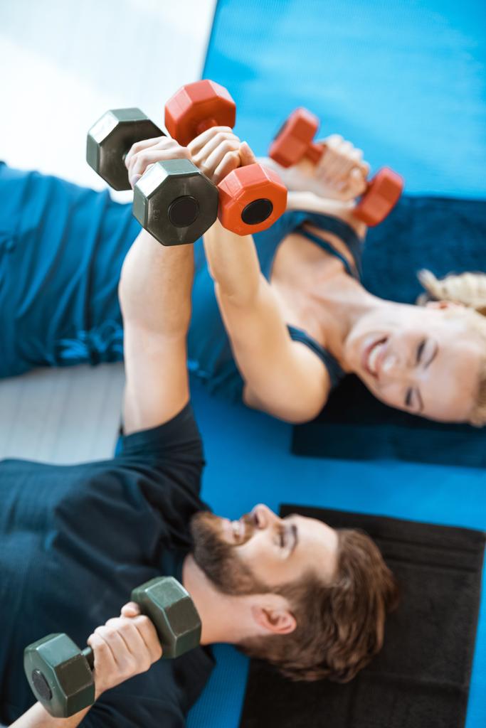 Paar jonge fitness mensen trainen met halters in fitnessstudio - Foto, afbeelding