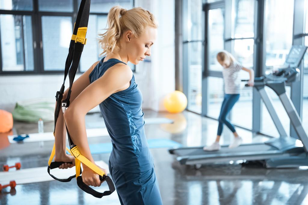 Blonde fitness vrouw trainen met trx fitness riemen - Foto, afbeelding