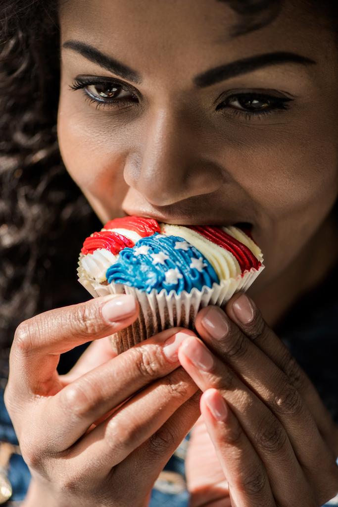 Amerikaans meisje beet cupcake - Foto, afbeelding