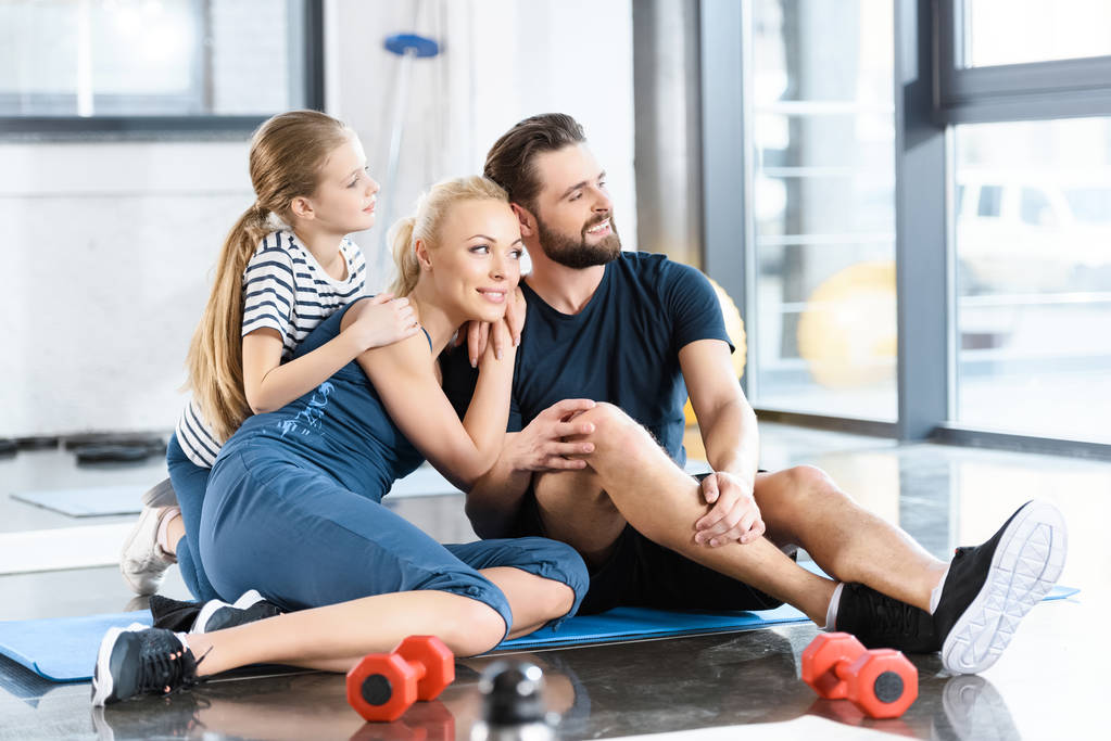 Retrato de la familia feliz sentado en la estera en el gimnasio
 - Foto, Imagen