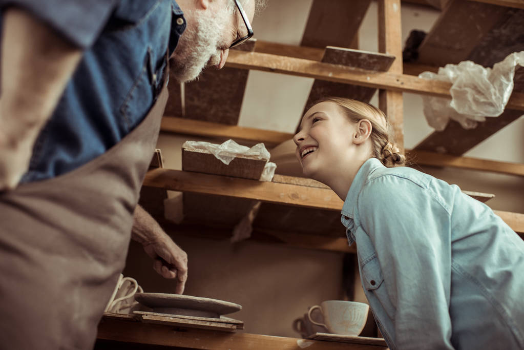 Großvater erklärt Enkelin, wie man Töpferscheibe bedient  - Foto, Bild