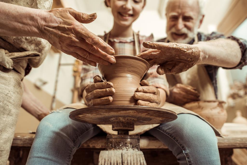 Бабушка и дедушка с внучкой делают керамику в мастерской
 - Фото, изображение