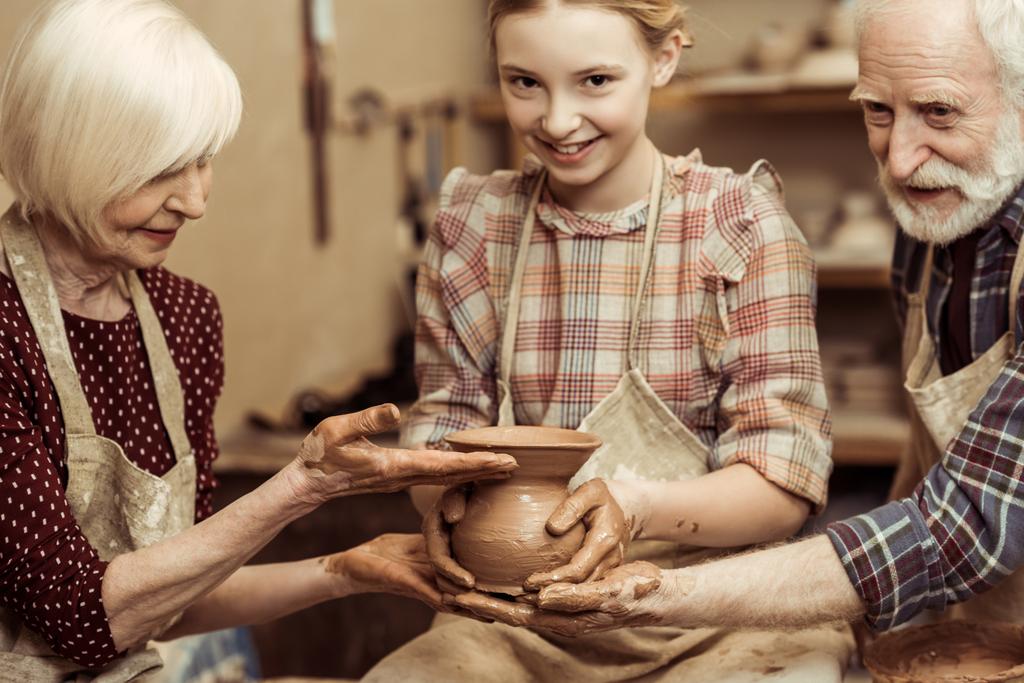 Abuela y abuelo con nieta haciendo cerámica en el taller
 - Foto, imagen