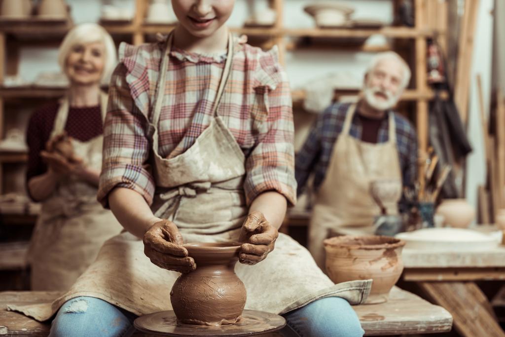 Бабушка и дедушка с внучкой делают керамику в мастерской
 - Фото, изображение