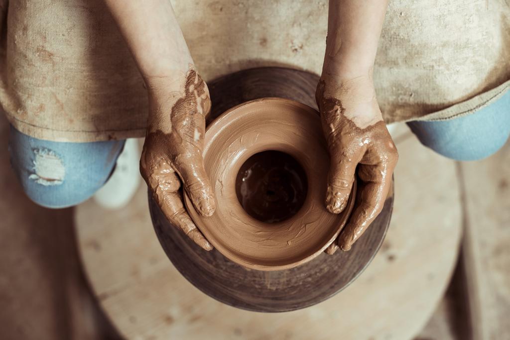 Close up de mãos de criança trabalhando na roda de cerâmica na oficina
 - Foto, Imagem