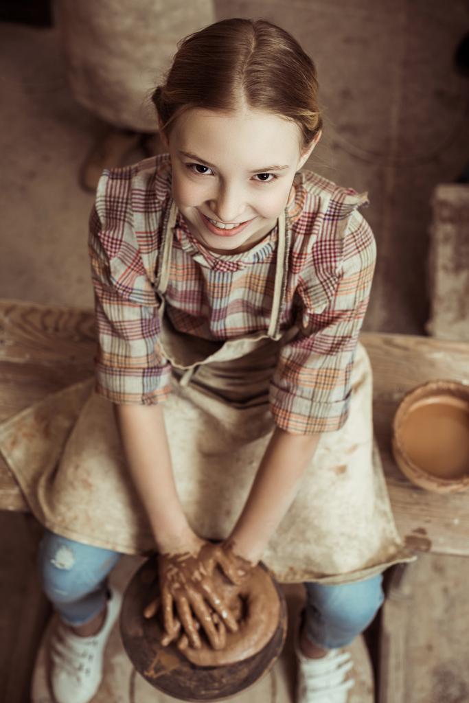 Vue aérienne de la petite fille faisant de la poterie sur roues à l'atelier
 - Photo, image