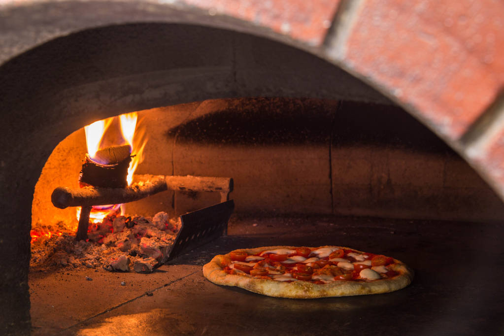 De hout oven op brandhout, voor het bakken van pizza. Open vuur.  - Foto, afbeelding