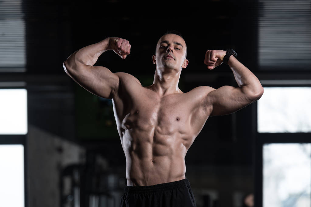 fisicoculturista modelo de fitness posando bíceps dobles después de los ejercicios
 - Foto, Imagen