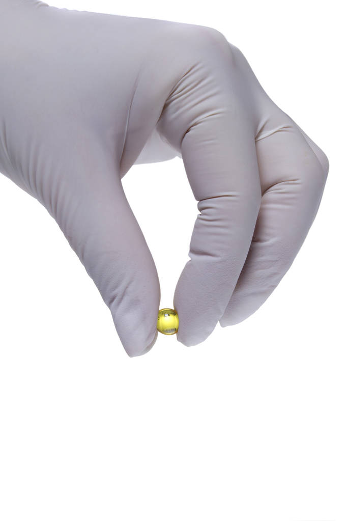 Hand in latex glove holding a pill - Photo, Image