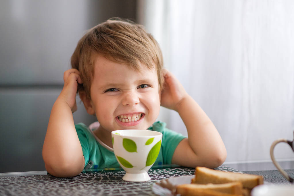 Веселий хлопчик п'є молоко, їсть тости на сніданок
 - Фото, зображення