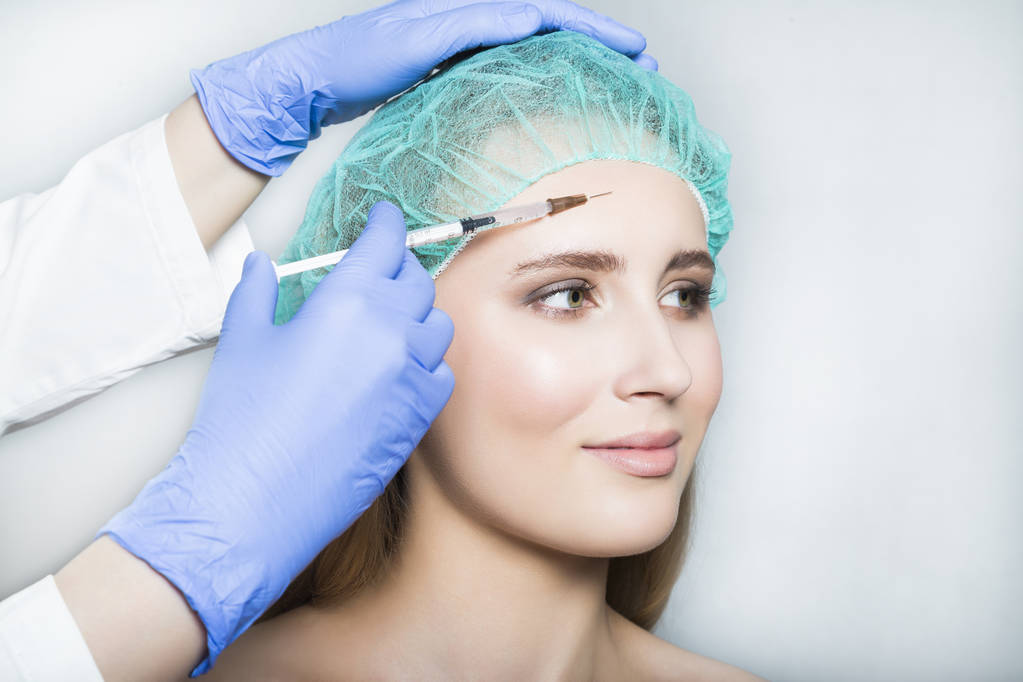 Dokter estheticus maakt gezicht schoonheid injecties aan vrouwelijke patiënt - Foto, afbeelding