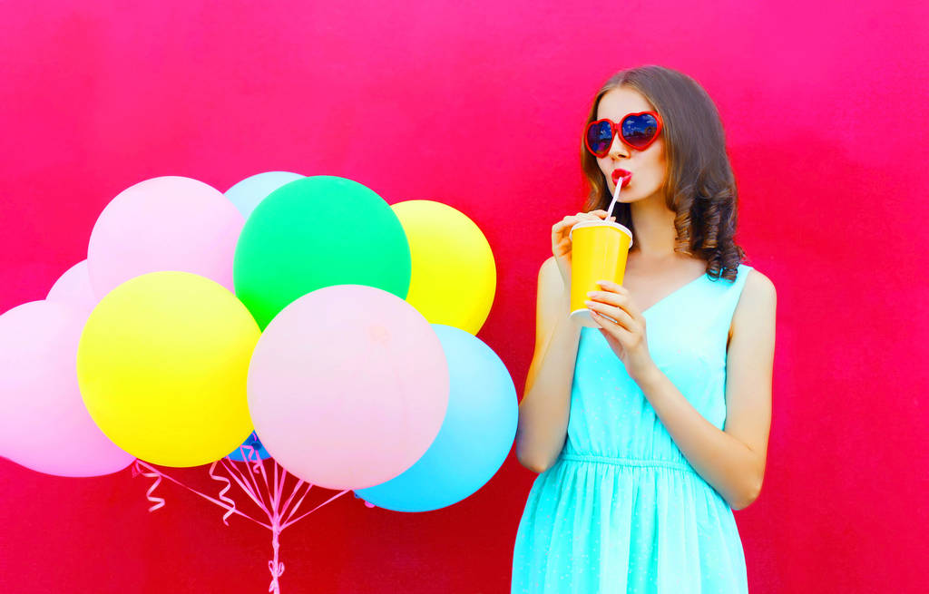 Щаслива молода жінка п'є фруктовий сік з чашки з повітряним коло
 - Фото, зображення