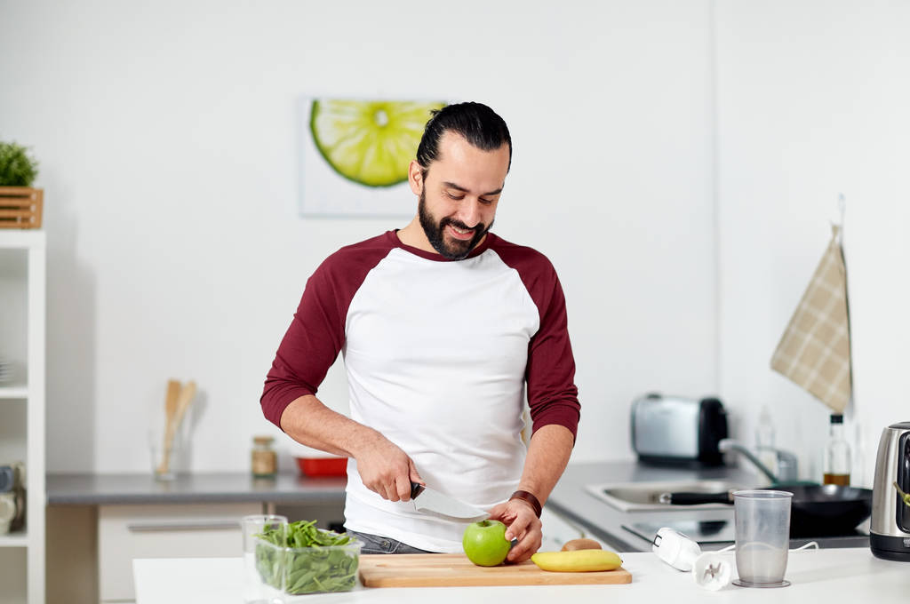 hombre con licuadora y cocina de frutas en la cocina casera
 - Foto, imagen