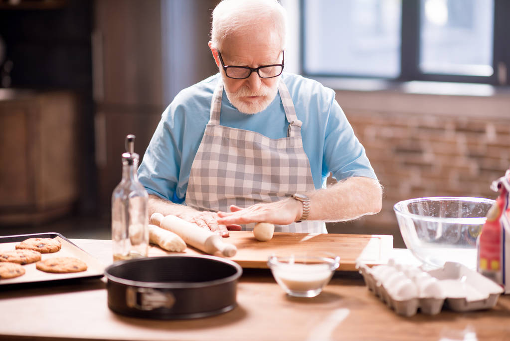 Homme âgé pétrissant la pâte
 - Photo, image