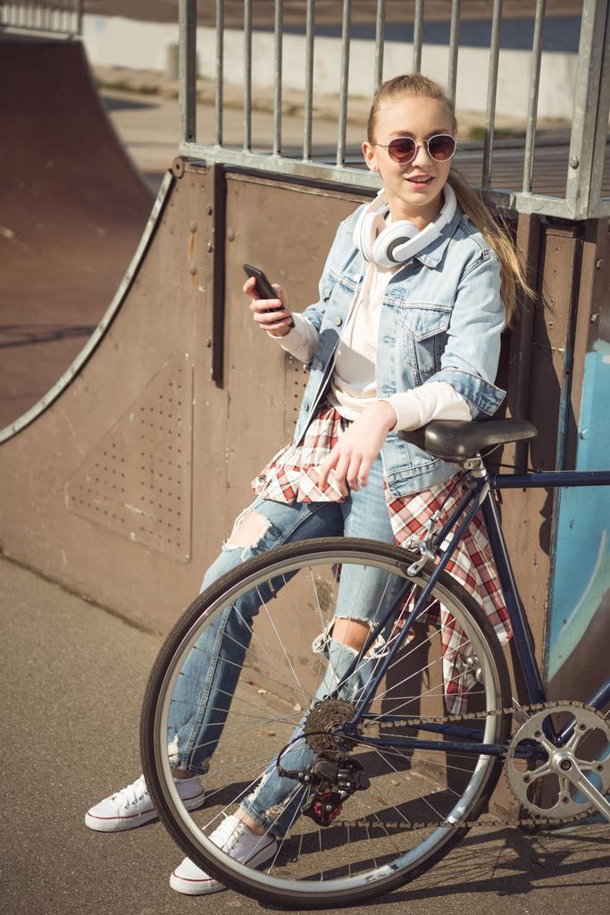 Κορίτσι με το ποδήλατο, χρησιμοποιώντας το smartphone  - Φωτογραφία, εικόνα