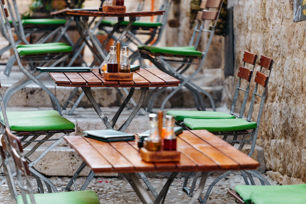 Puiset tuolit ja pöydät ruokalistalla, suolalla ja öljyllä eurooppalaisessa katukahvilassa tai ravintolassa
 - Valokuva, kuva
